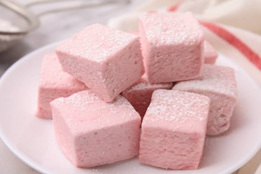 Plate of delicious sweet marshmallows with powdered sugar on table, closeup