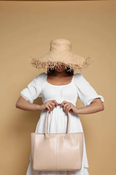 Young woman with stylish bag on beige background