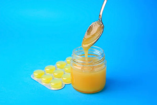 Blister with cough drops and honey on light blue background