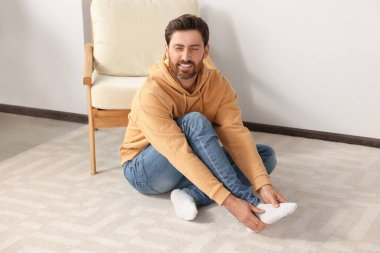 Man massaging leg on soft carpet at home