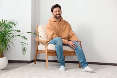 Man suffering from leg pain on soft armchair indoors