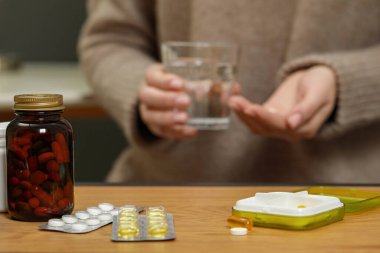 Plastic pill box with different medicaments on wooden table, space for text