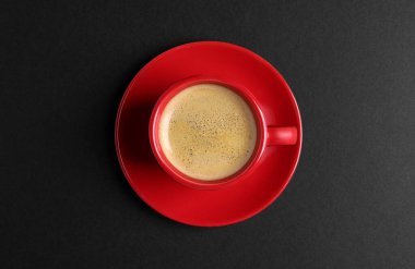 Red ceramic cup with hot aromatic coffee on black background, top view