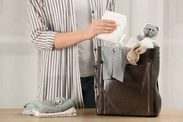 Woman Putting Diaper Mother Bag Wooden Table Indoors Closeup — 스톡 사진