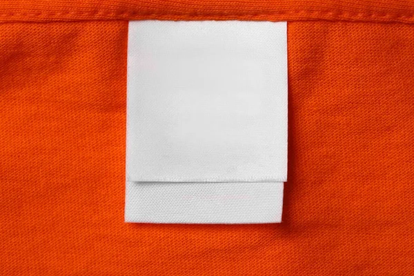 Clothing label on orange garment, top view