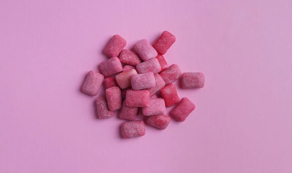 Heap of tasty sweet chewing gums on pink background, flat lay