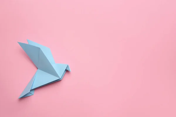 Beautiful light blue origami bird on pink background, top view. Space for text