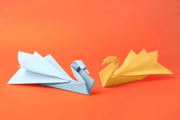 Origami art. Beautiful paper swans on orange background