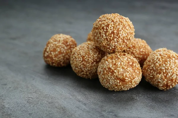 Many delicious sesame balls on grey table, closeup. Space for text