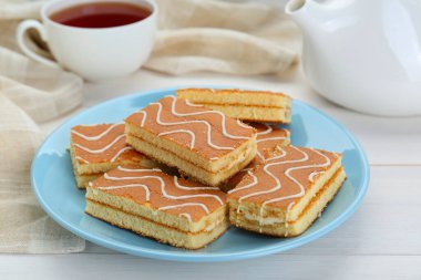 Tasty sponge cakes and hot drink on while wooden table