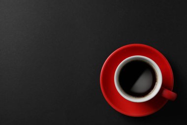 Cup with aromatic coffee on black background, top view. Space for text