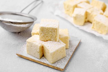 Delicious sweet marshmallows with powdered sugar on light grey table
