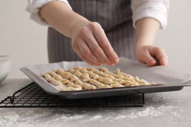 Woman making traditional grissini at light grey marble table, closeup