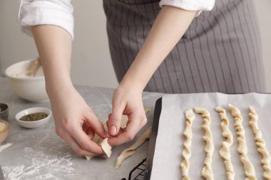 Woman making traditional grissini at light grey marble table, closeup