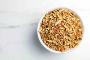 Bowl of dried orange zest seasoning on white marble table, top view. Space for text