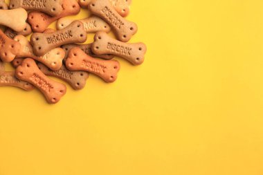 Bone shaped dog cookies on yellow background, flat lay. Space for text