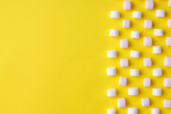 Delicious puffy marshmallows on yellow background, flat lay. Space for text