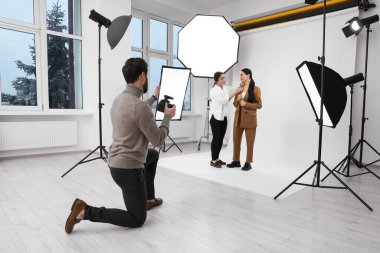 Professional photographer and assistant working with beautiful model in modern photo studio