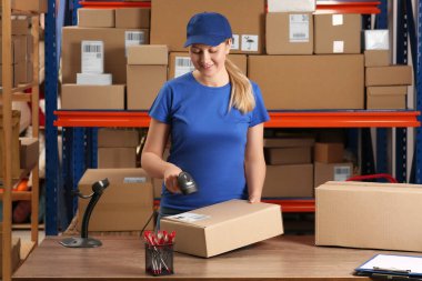 Post office worker with scanner reading parcel barcode at counter
