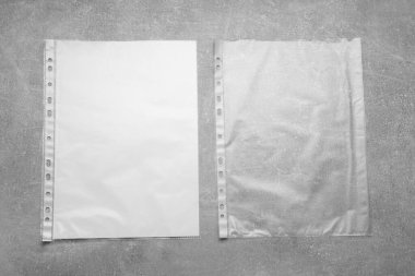 Punched pockets on grey table, flat lay. Space for text