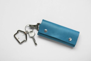 Leather case with key on light grey background, top view