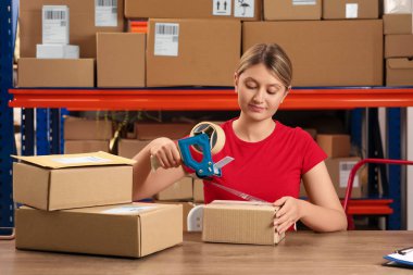 Post office worker packing parcel at counter indoors