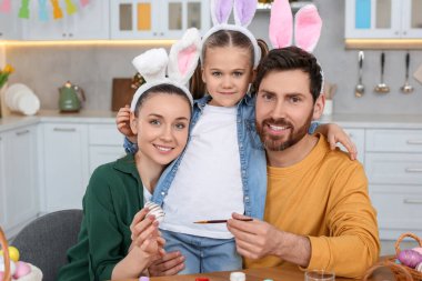 Happy family with Easter eggs at table in kitchen
