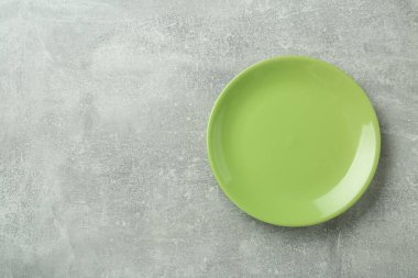 Clean green plate on grey table, top view. Space for text