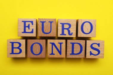 Word Eurobonds made of wooden cubes with letters on yellow background, flat lay