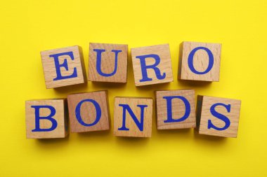 Word Eurobonds made of wooden cubes with letters on yellow background, flat lay