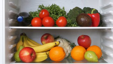 Open refrigerator with many different fresh vegetables and fruits