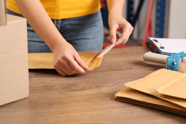 Post office worker with adhesive paper bag at counter indoors, closeup