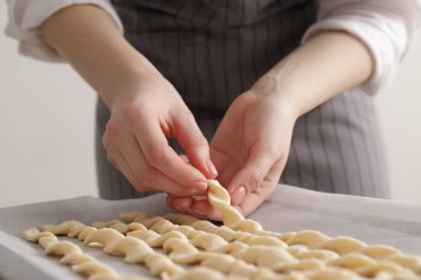 Woman with traditional grissini on light grey background, closeup