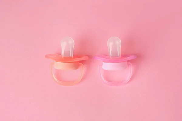 New baby pacifiers on pink background, flat lay