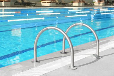 Ladder with handrails in outdoor swimming pool