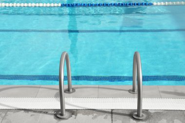 Ladder with handrails in outdoor swimming pool