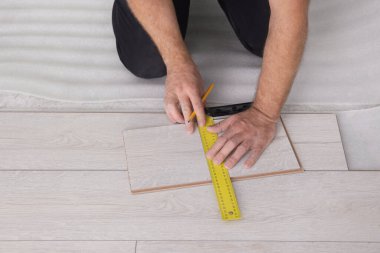 Man using measuring tape during installation of laminate flooring, closeup