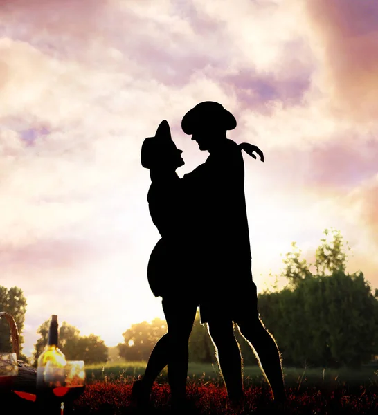 Silhouette of lovely couple hugging on picnic in park