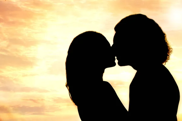 Silhouette of lovely couple kissing at sunset