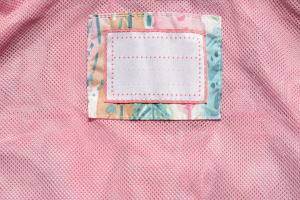 Clothing label on pink garment, top view