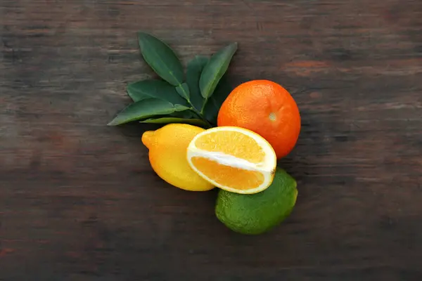 木のテーブルの上に異なる柑橘類や葉 フラットレイアウト — ストック写真