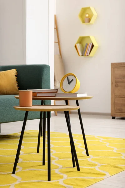 Spring interior. Yellow clock, books and candle on wooden table in living room