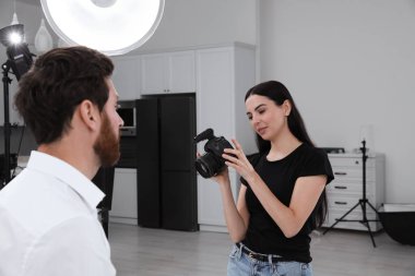 Professional photographer working with handsome model in modern photo studio