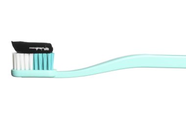 Brush with charcoal toothpaste against white background