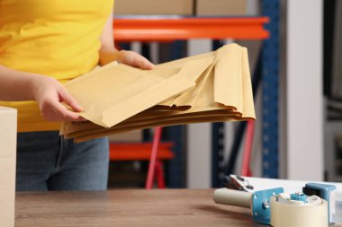 Post office worker with adhesive paper bags at counter indoors, closeup