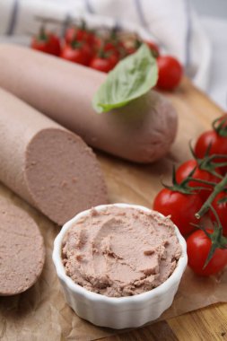 Delicious liver sausages, paste and cherry tomatoes on wooden board, closeup