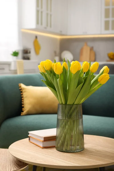 Spring interior. Bouquet of beautiful yellow tulips and books on wooden table in living room