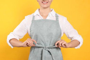Woman in clean apron with pattern on orange background, closeup