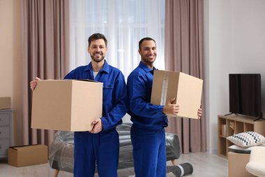 Male movers with cardboard boxes in new house
