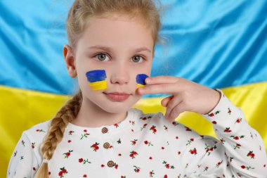 Little girl with face paint near Ukrainian flag